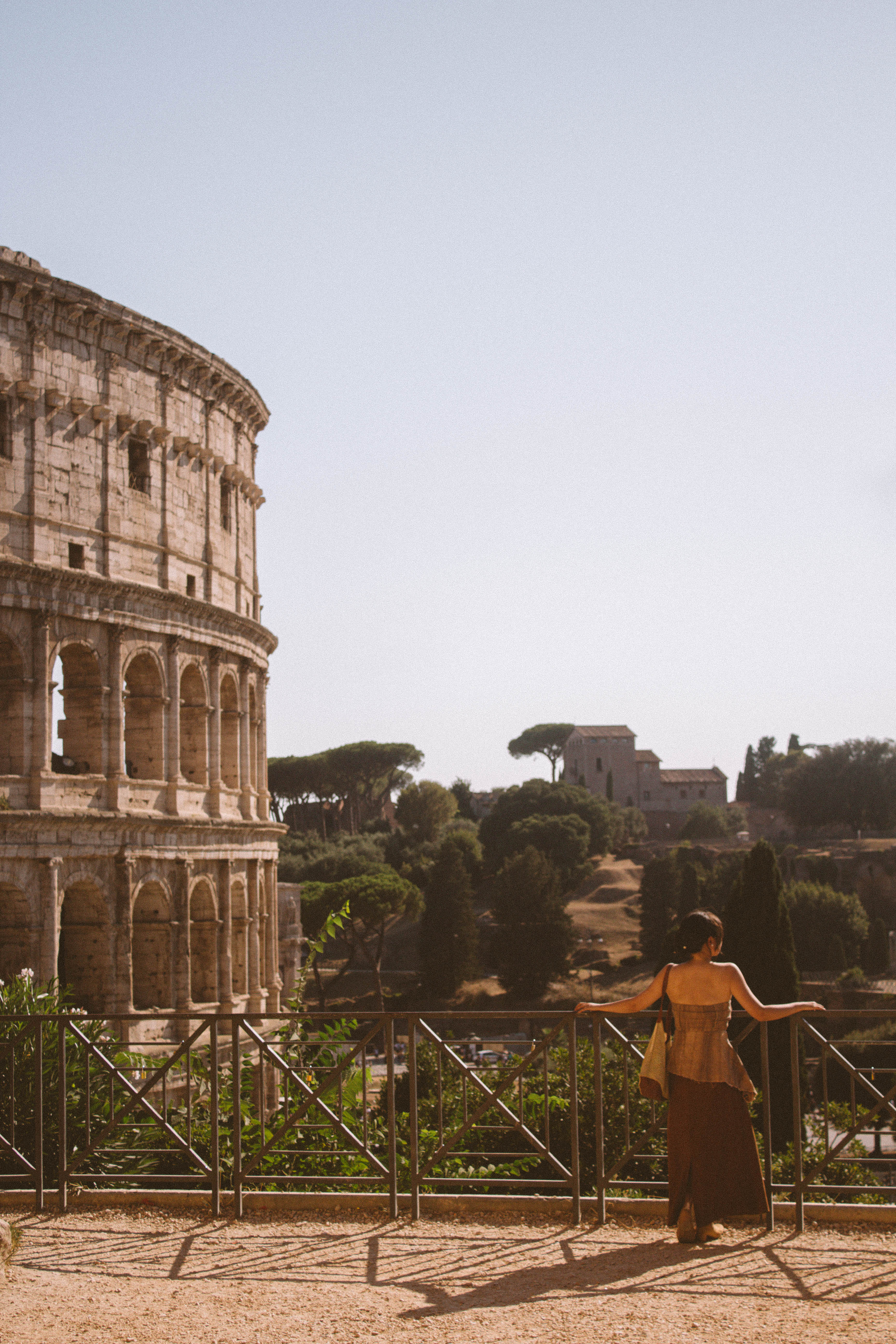 Person in flowing dress overlooking the Roman Colosseum at golden hour