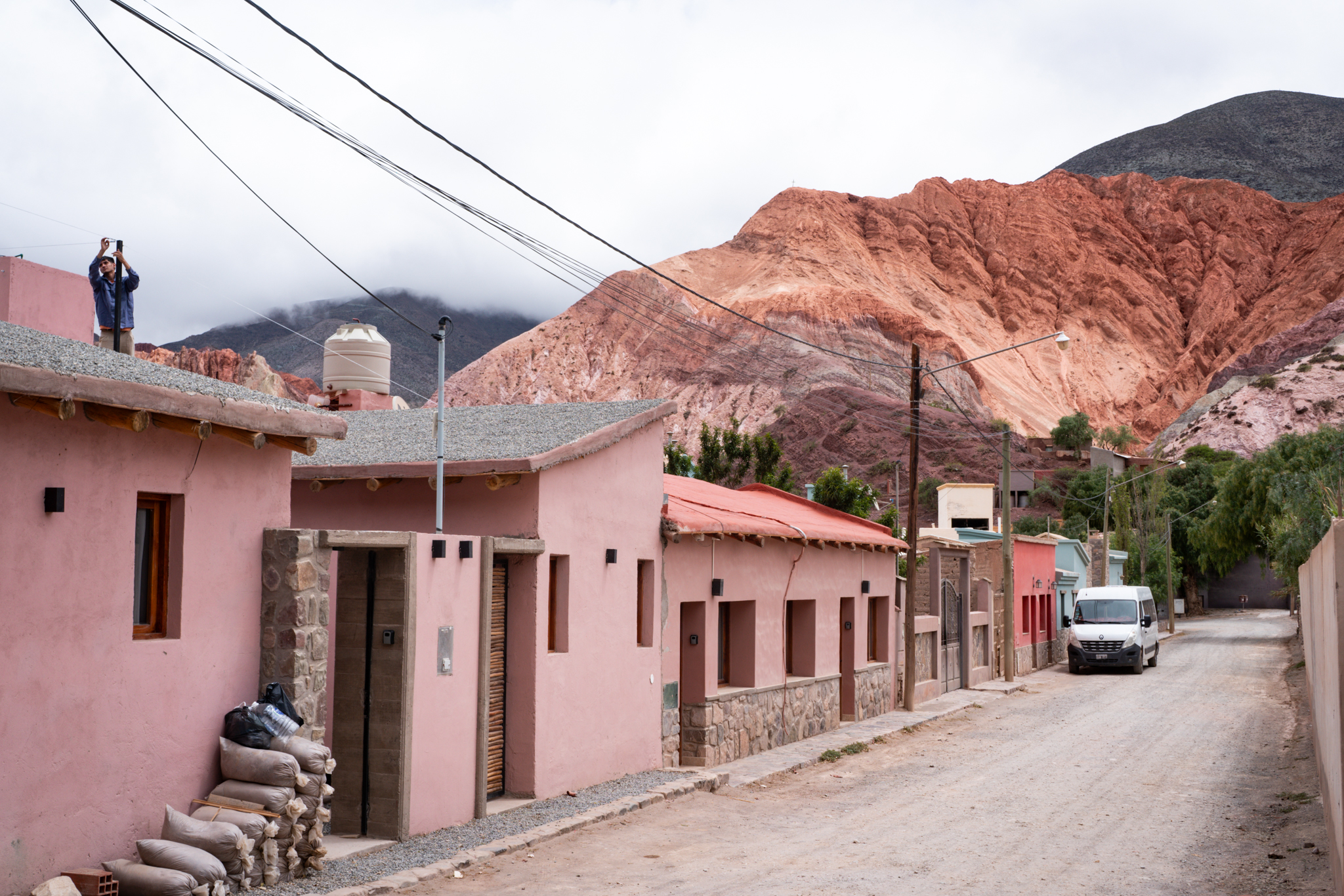 Traditional pink adobe houses with dramatic red rock mountain backdrop