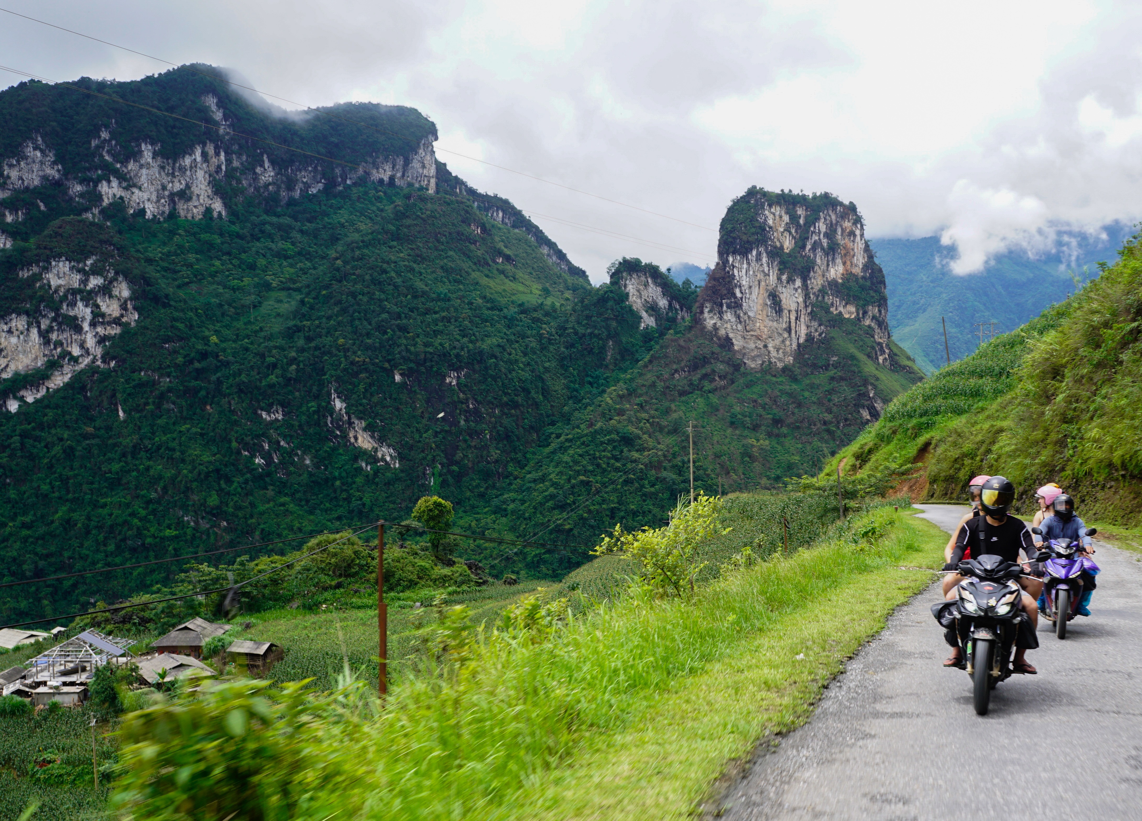 Motorcyclists navigating through lush green karst mountains in Southeast Asia